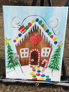 a painting of a gingerbread house decorated with candy canes and candies on a easel