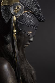 a woman with black skin and gold accents wearing a headdress in the dark