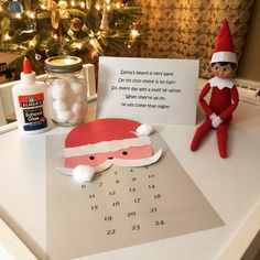 an elf's calendar is sitting on the counter next to a christmas tree