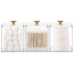 three clear acrylic boxes with gold handles and white cotton balls in each container