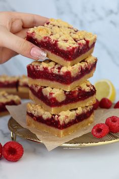 a hand is picking up some raspberry crumbs from a stack on a plate