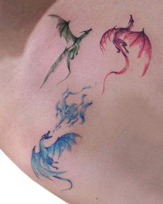 the back of a woman's shoulder with three different colored dragon tattoos on it