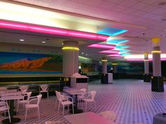 an empty restaurant with checkered flooring and colorful lights on the ceiling above it