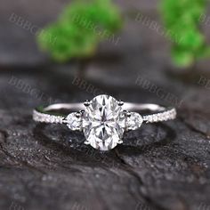 a diamond engagement ring with three stones on the side, sitting on top of a piece of wood