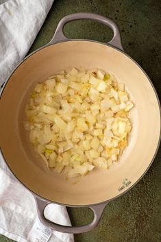 onions are being cooked in a skillet on the stove top next to a white towel