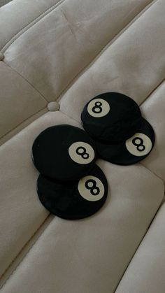 three black and white buttons sitting on the back of a couch with no one in it