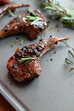 grilled lamb chops with rosemary garnish on a baking sheet, ready to be served