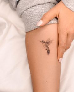 a woman's arm with a small tattoo of a hummingbird on her left side