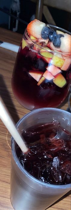 a bowl filled with fruit next to a metal container full of liquid on top of a wooden table