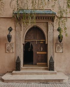 an entrance to a building with carved wooden doors and pillars on the outside, surrounded by greenery