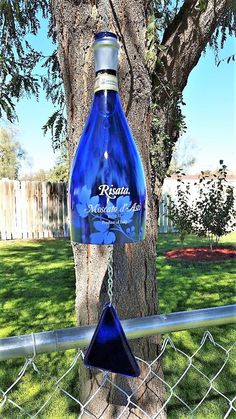 a blue bottle hanging from the side of a tree in front of a chain link fence