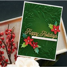 a christmas card with holly and poinsettis on it next to some flowers