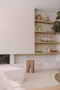 a living room filled with furniture and a fire place in front of a stone wall