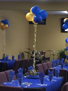 blue and gold balloons are on top of the centerpieces in this banquet room