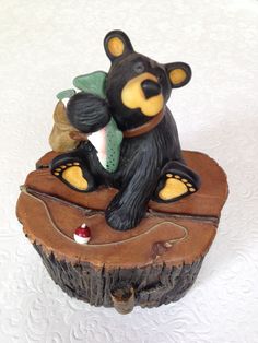 a bear figurine sitting on top of a piece of wood