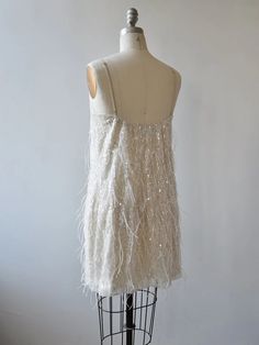 a mannequin wearing a white dress with feathers on it