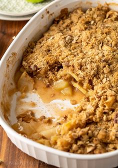 a casserole dish with apples and crumbled toppings in a white dish on a wooden table