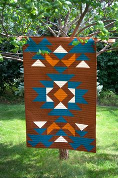 a brown and blue quilt hanging from a tree