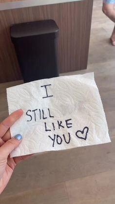 someone holding up a piece of paper with writing on it that says i still like you