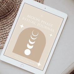 the moon phase ritual journal on an ipad next to a straw hat and straw bag