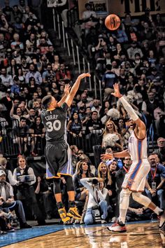 two men playing basketball in front of an audience with their arms up to the ball