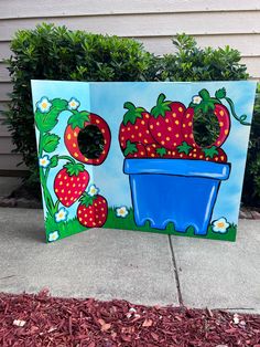 a painting of strawberries in a blue flower pot on the side of a house