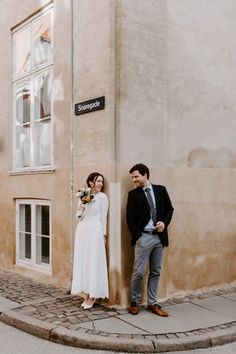 a man and woman standing next to each other near a building with a street sign on it