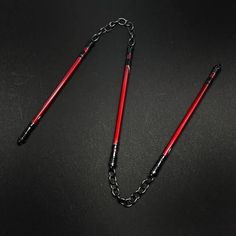 two red canes on a black surface with a chain attached to the end of them