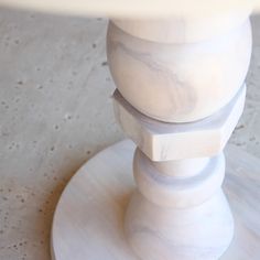 a close up of a white table with a marble pedestal on the top and bottom