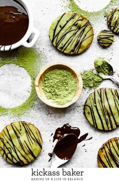 chocolate covered cookies and green powder on a white surface with spoons next to them