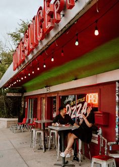 two people sitting at tables in front of a restaurant