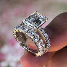 a person is holding a ring with an emerald and diamond center stone in their hand