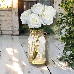 white roses in a mason jar sitting on a wooden table