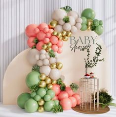 a baby shower backdrop with balloons and greenery