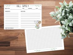 two notepads sitting on top of a wooden table next to a potted plant