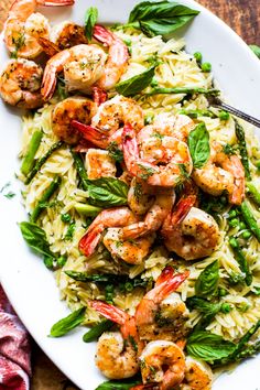 pasta with shrimp, asparagus and spinach on a white plate next to a fork