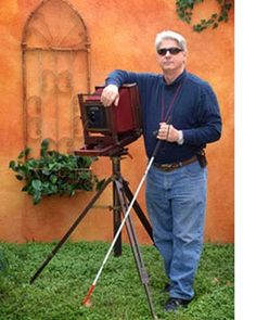 a man standing next to a camera on top of a tripod in the grass