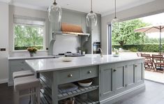 a large kitchen with an island in the middle and two pendant lights hanging from the ceiling