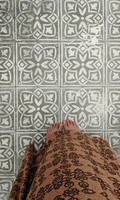 a person laying on the ground with their feet propped up in front of a patterned wall