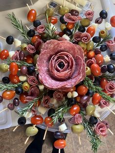 an arrangement of meats, olives and tomatoes on skewers with toothpicks