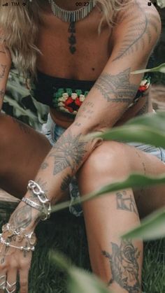 a woman with tattoos sitting in the grass