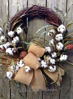 a wreath made out of burlock and cotton is hanging on a wooden fence