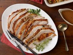 sliced pork on a white plate with garnishes and silverware next to it