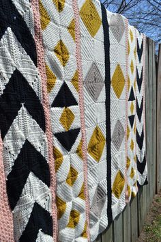 a quilt is hanging on the side of a fence