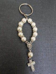 a keychain with a cross and pearls attached to the clasp on a black background