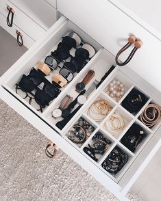 an open drawer filled with lots of glasses and other items on top of carpeted floor