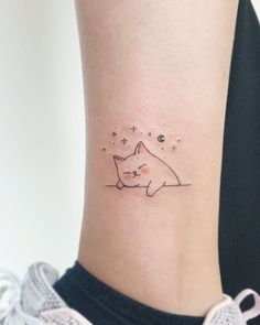 a small tattoo on the ankle of a woman's left leg, with an image of a cat