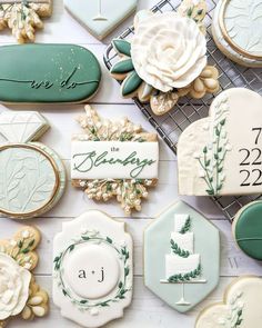 decorated cookies and cookie cutters are arranged on a white wooden surface with the names of their guests