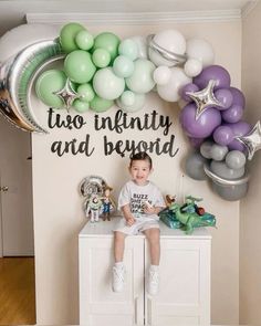 a little boy sitting on top of a dresser in front of balloons and heliums