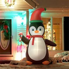 an inflatable penguin is standing next to a house with christmas decorations on it